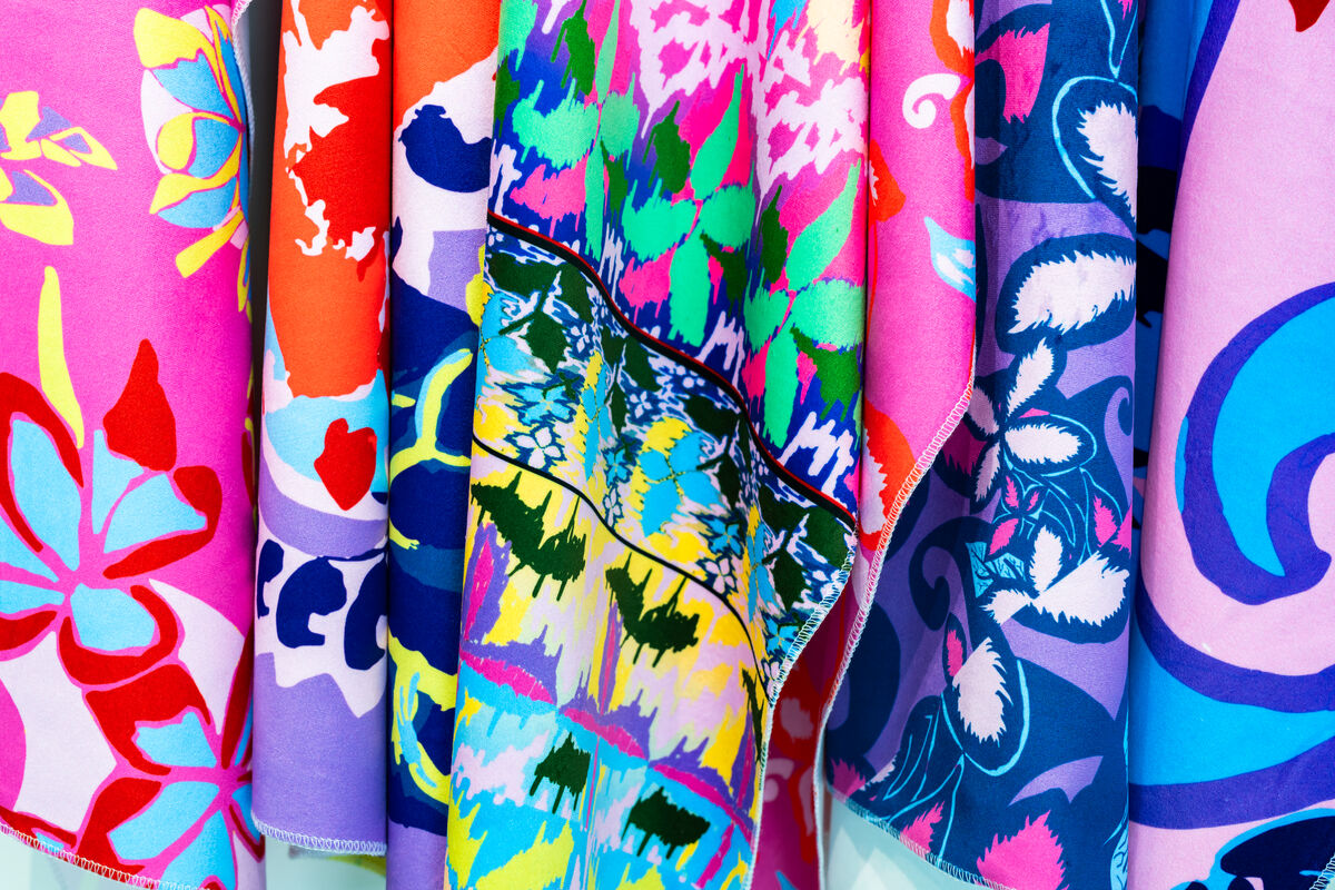 Several brightly coloured, silk fabrics covered in different floral patterns. They are hung up and folded around each other.